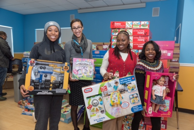 ABCD Toy Drive team members hold holiday toys to be given to underserved children.
